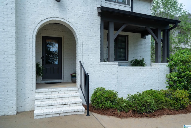 view of exterior entry with covered porch and brick siding
