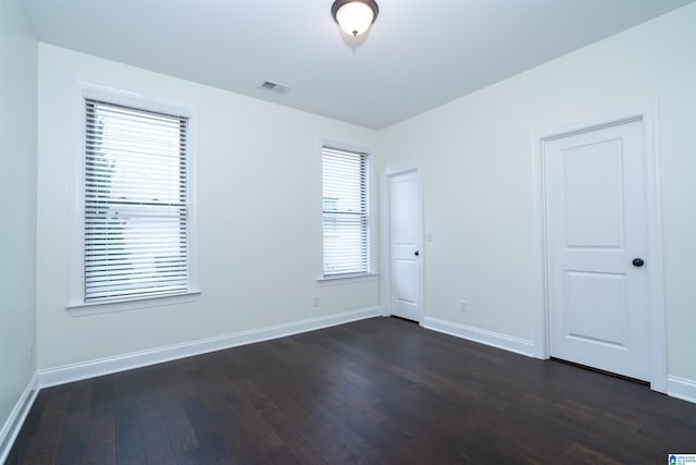unfurnished room featuring dark wood-style floors, baseboards, and visible vents