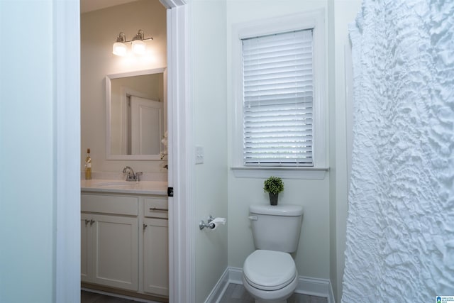 full bathroom featuring baseboards, toilet, and vanity