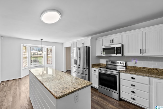 kitchen with stone countertops, dark wood-style flooring, a center island, appliances with stainless steel finishes, and white cabinetry