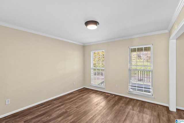 empty room featuring dark wood-type flooring, a wealth of natural light, baseboards, and ornamental molding