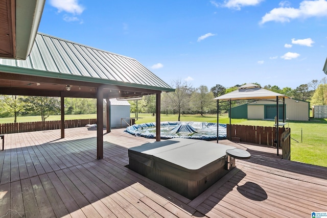 wooden deck featuring a gazebo, hot tub deck surround, a storage shed, a lawn, and an outdoor structure