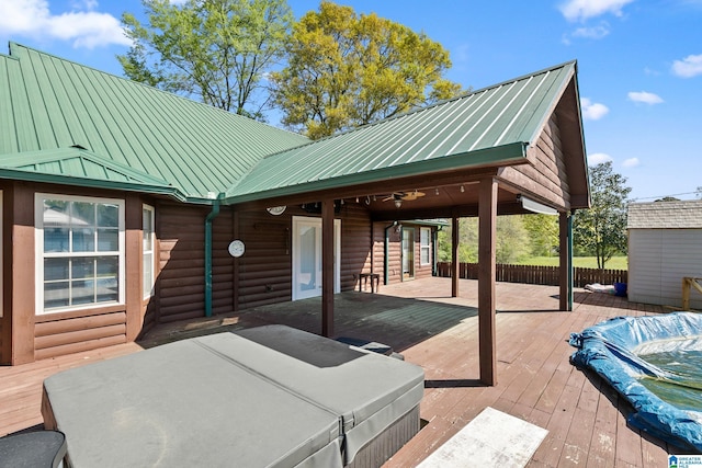 view of patio with a wooden deck, an outdoor hot tub, and fence