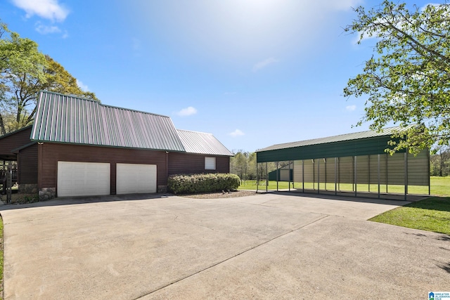 exterior space featuring a garage, driveway, an outbuilding, and metal roof