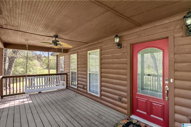 view of exterior entry with ceiling fan and faux log siding