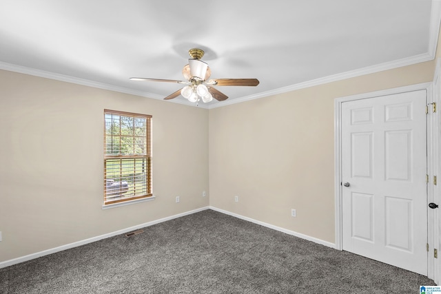 empty room with dark colored carpet, a ceiling fan, baseboards, and ornamental molding