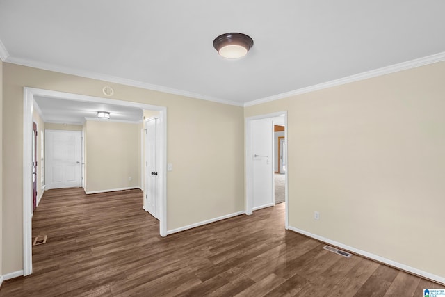 empty room with dark wood-style flooring, ornamental molding, visible vents, and baseboards