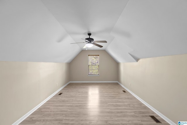 additional living space featuring light wood-type flooring, baseboards, visible vents, lofted ceiling, and a ceiling fan