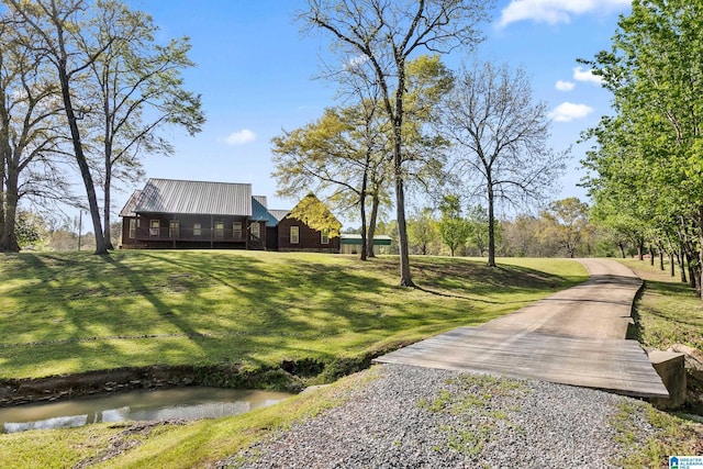 view of property's community with gravel driveway and a yard