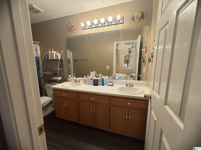 full bathroom with double vanity, visible vents, toilet, and a sink