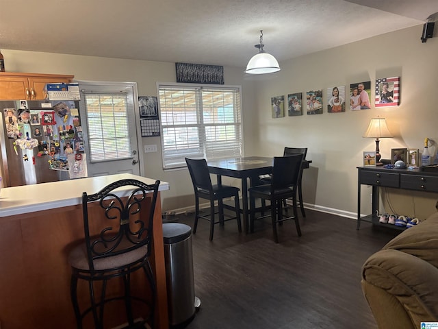 dining room with dark wood-type flooring, plenty of natural light, and baseboards