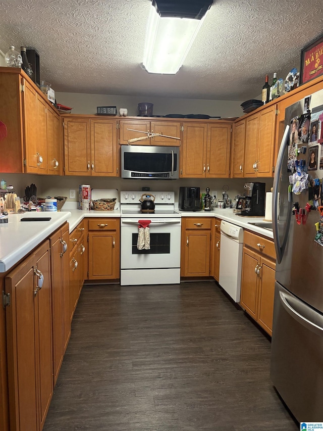 kitchen with stainless steel appliances, light countertops, a textured ceiling, and dark wood-style flooring