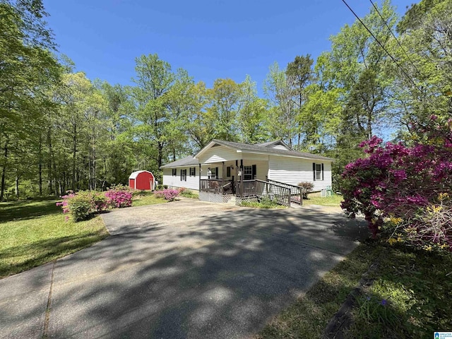 bungalow-style home with a shed, driveway, covered porch, an outdoor structure, and a front yard