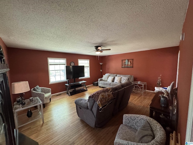 living area with baseboards, a textured ceiling, hardwood / wood-style flooring, and ceiling fan