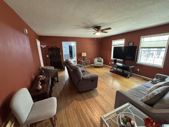 living area with hardwood / wood-style floors, a ceiling fan, baseboards, and a textured ceiling