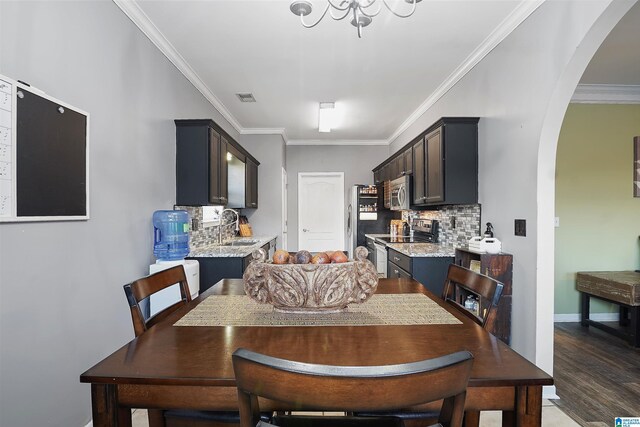 dining area with wood finished floors, visible vents, arched walkways, crown molding, and baseboards