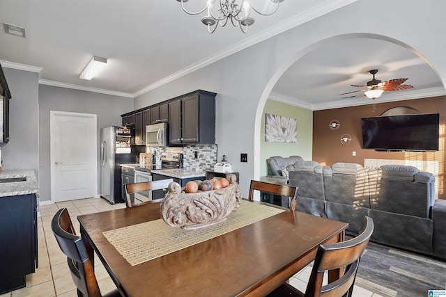 dining space with arched walkways, visible vents, ornamental molding, and ceiling fan with notable chandelier