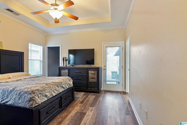 bedroom featuring a tray ceiling, visible vents, crown molding, and dark wood-type flooring