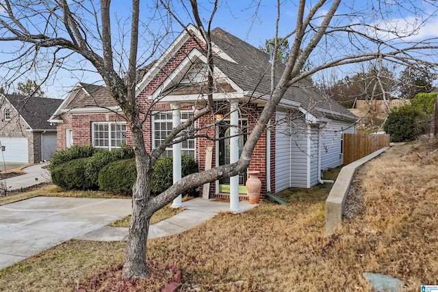 view of front of home featuring fence, a shingled roof, brick siding, and a front yard