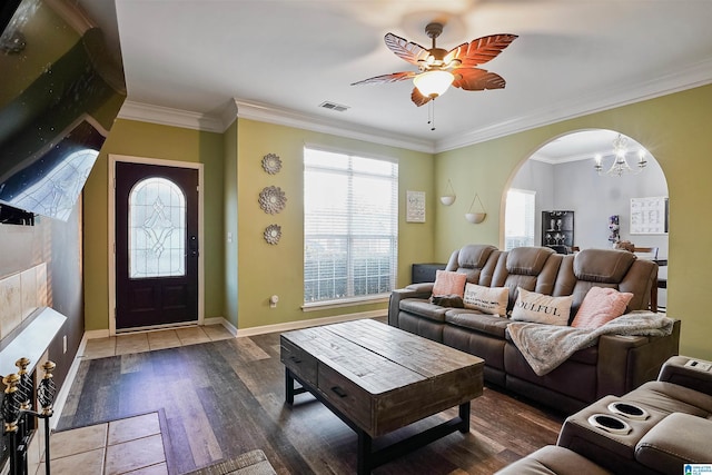 living area featuring visible vents, arched walkways, crown molding, baseboards, and ceiling fan with notable chandelier