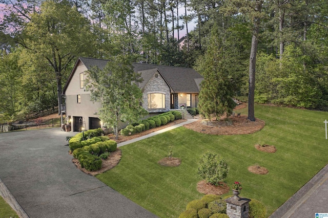 view of front of house featuring an attached garage, a front yard, stone siding, and concrete driveway