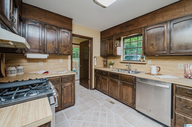 kitchen with light countertops, dark brown cabinets, a sink, tasteful backsplash, and appliances with stainless steel finishes