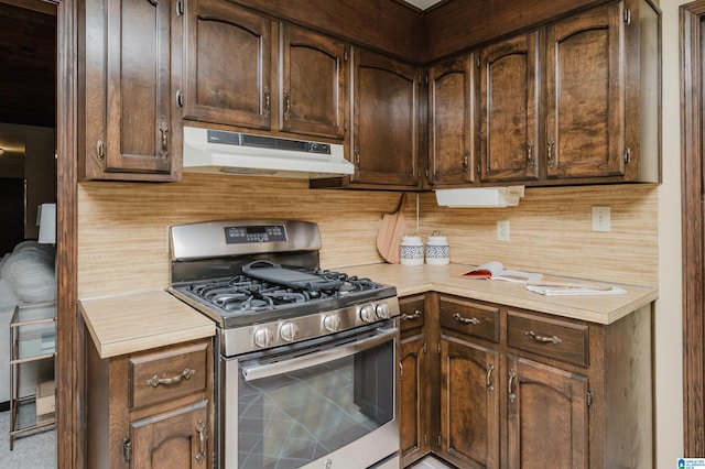 kitchen featuring dark brown cabinets, light countertops, under cabinet range hood, and gas range