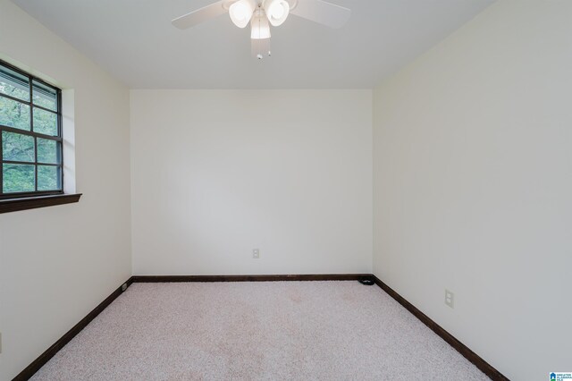 carpeted spare room with a ceiling fan and baseboards
