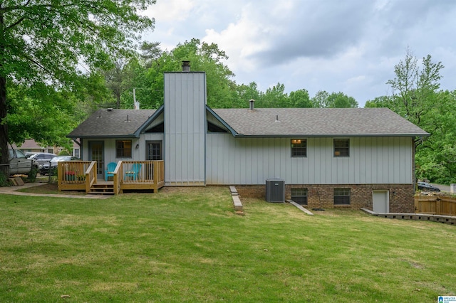 rear view of property featuring a chimney, a wooden deck, fence, and a yard