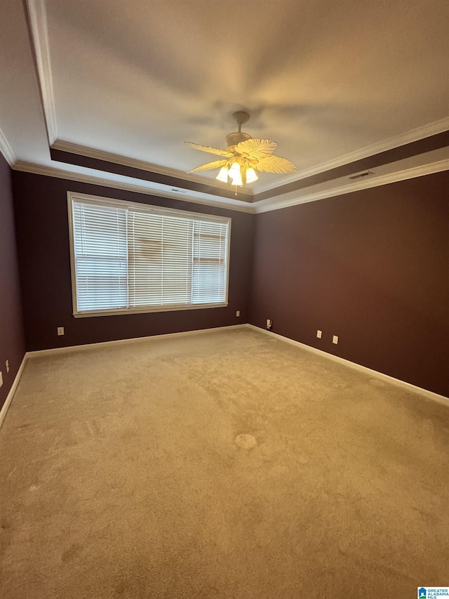 carpeted spare room featuring ceiling fan, baseboards, crown molding, and a tray ceiling