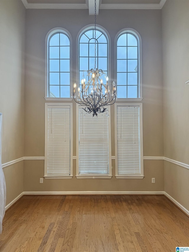 interior space featuring light wood-style floors, crown molding, baseboards, and an inviting chandelier