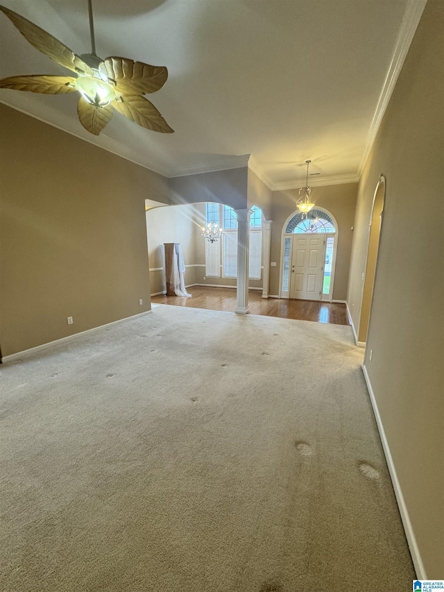 interior space featuring baseboards, crown molding, carpet flooring, and ceiling fan with notable chandelier