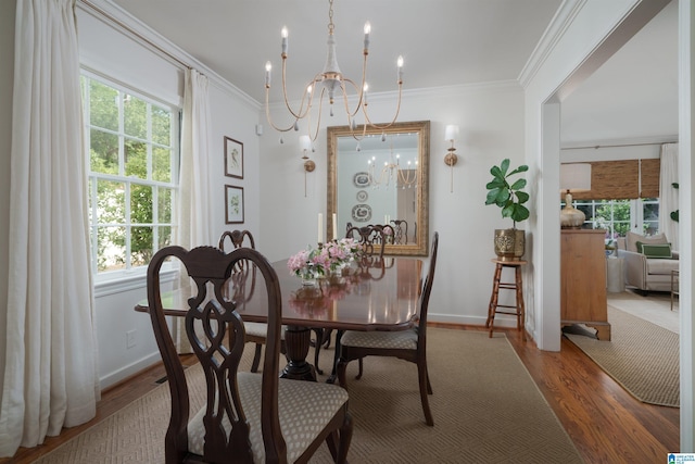 dining room featuring a chandelier, baseboards, wood finished floors, and crown molding