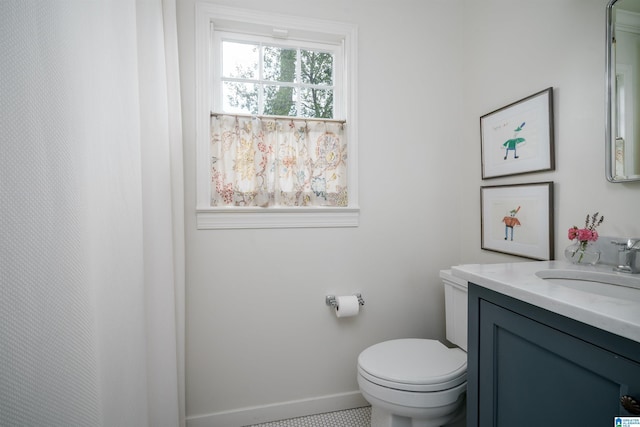 bathroom featuring toilet, vanity, and baseboards