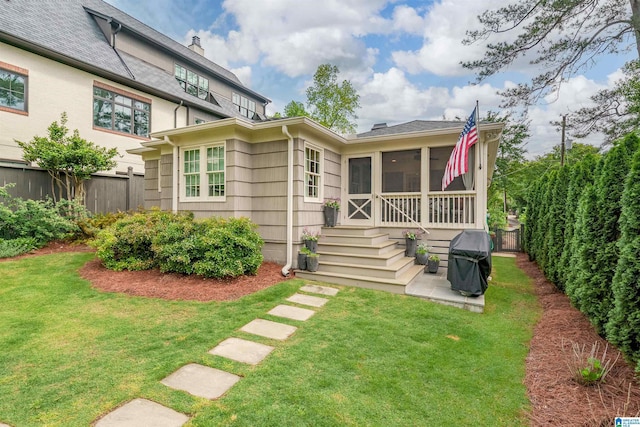 back of house featuring a chimney, fence, a yard, and a sunroom