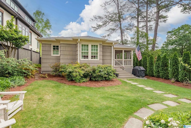 back of property featuring fence, a yard, and a sunroom