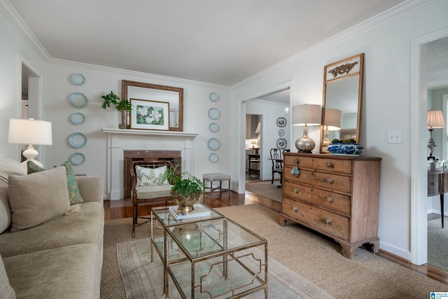 living area featuring a fireplace, wood finished floors, crown molding, and baseboards