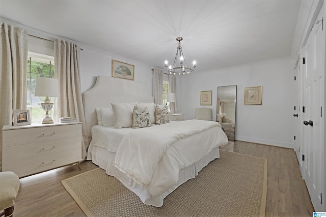 bedroom with an inviting chandelier, crown molding, and wood finished floors