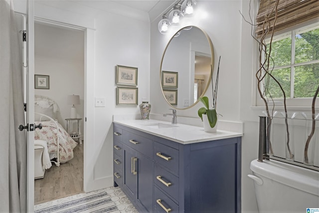 bathroom with connected bathroom, crown molding, vanity, toilet, and wood finished floors