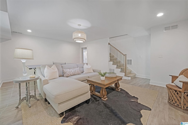 living room featuring visible vents, light wood-style floors, and stairway