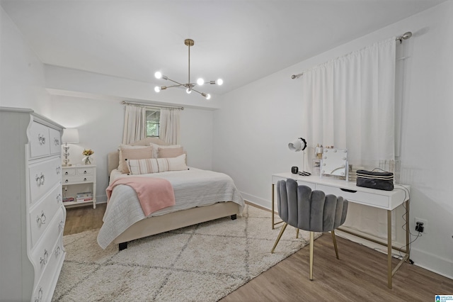 bedroom featuring an inviting chandelier, baseboards, and wood finished floors