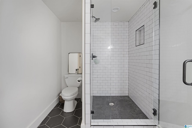 bathroom with baseboards, tile patterned flooring, a shower stall, and toilet