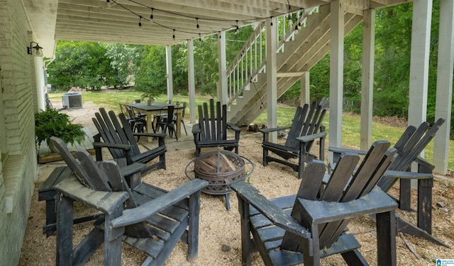 view of patio / terrace featuring stairs, central AC unit, an outdoor fire pit, and outdoor dining space