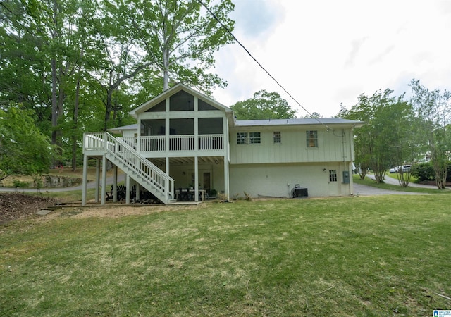 rear view of property featuring a deck, a sunroom, stairway, central AC, and a yard