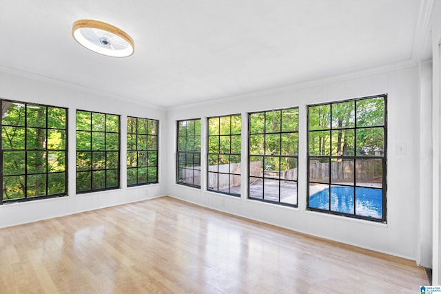 unfurnished sunroom featuring ornamental molding and wood finished floors