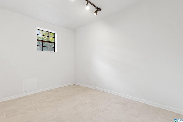 spare room with baseboards and rail lighting
