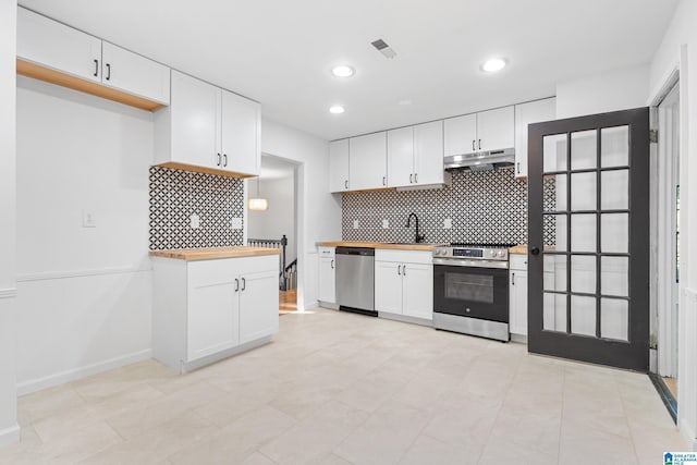 kitchen featuring white cabinetry, a sink, appliances with stainless steel finishes, wooden counters, and under cabinet range hood