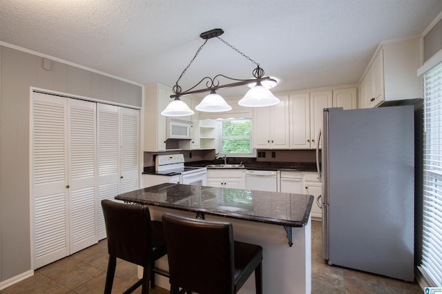 kitchen with a breakfast bar area, crown molding, a sink, white cabinets, and white appliances