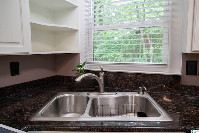 room details with a sink, white cabinetry, dark stone countertops, and tasteful backsplash