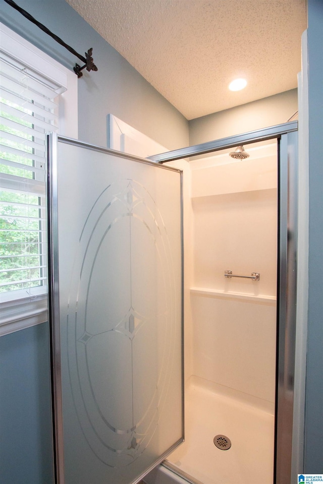 full bath featuring a shower stall and a textured ceiling